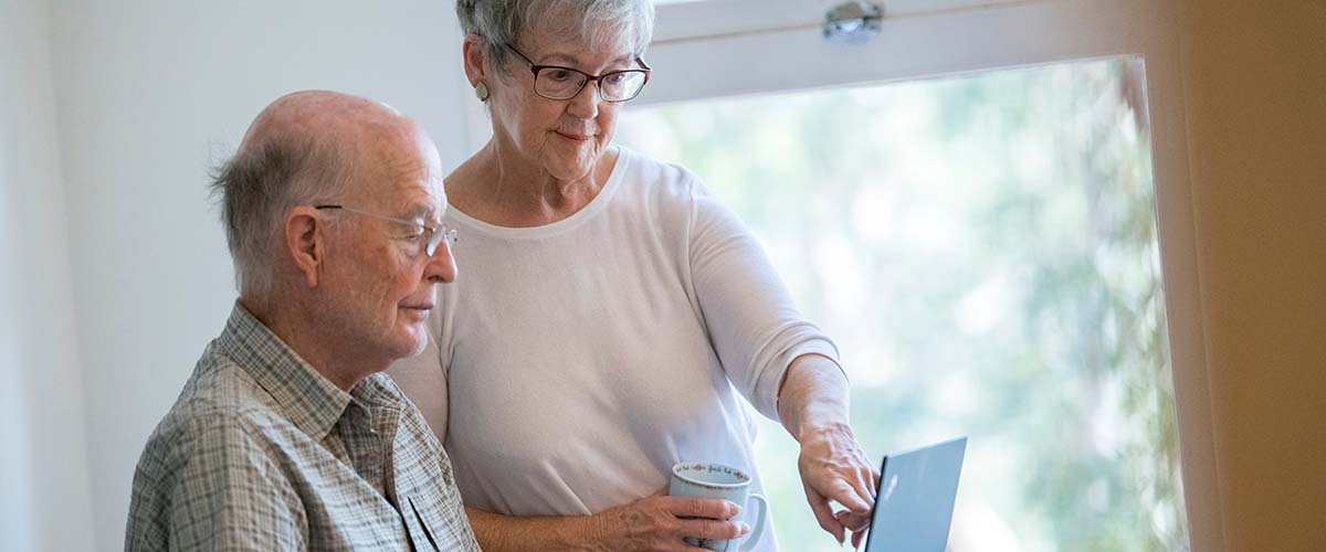 Elderly couple reading something on their laptop 