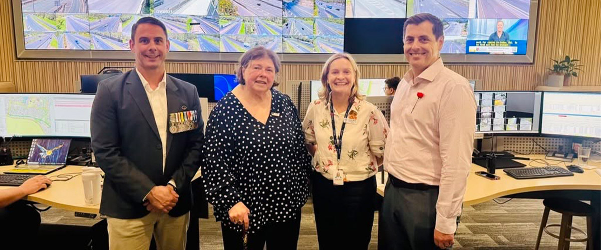 Four people stand in front of a screen at a traffic control centre.