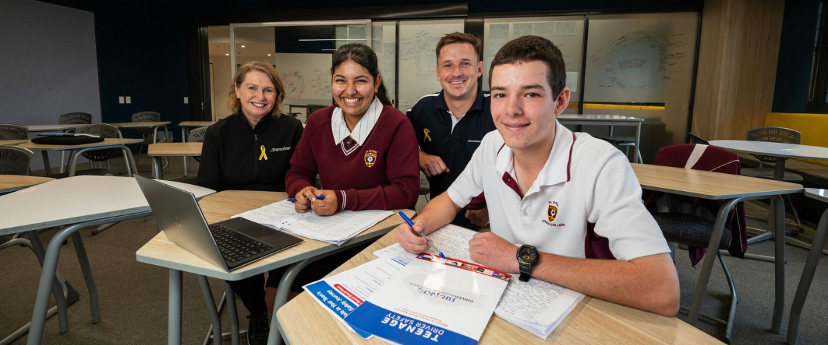 Four people sitting at desks in a classroom.